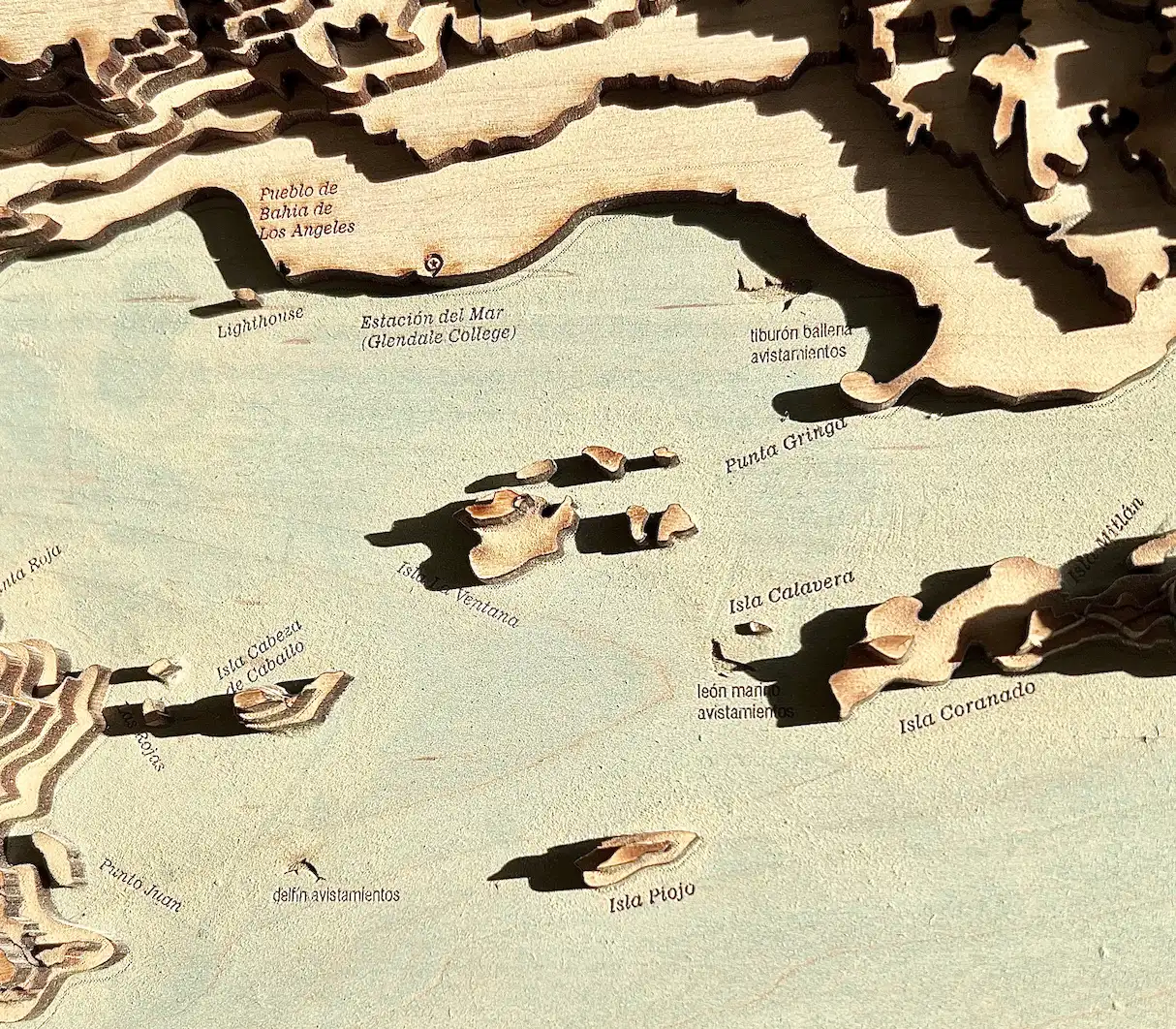 Full view of the 8-by-10-inch Bahía de los Ángeles map showing the complete bay with its scattered islands. A title block at the bottom reads 'Bahia De Los Angeles, México' with coordinates and scale. The layered coastline creates dramatic shadows against the pale turquoise water.